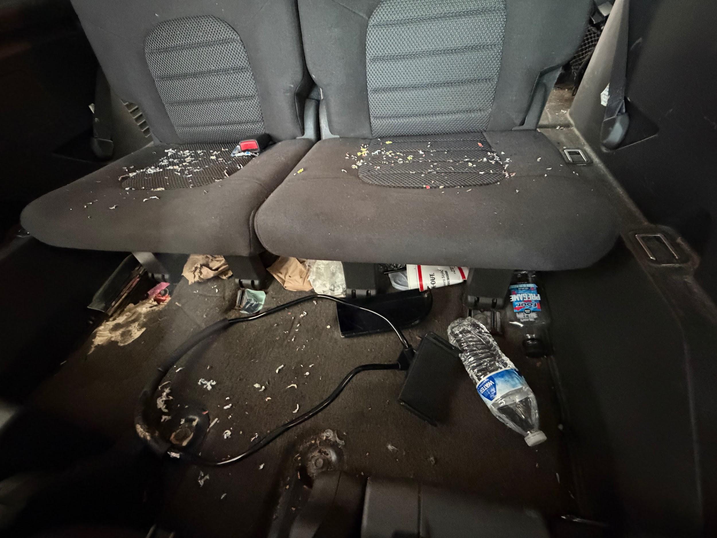 Nissan Pathfinder rear seats with trash and food debris before detailing